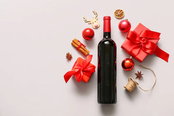 Bottle of wine with different spices, Christmas decorations and gift boxes on white background
