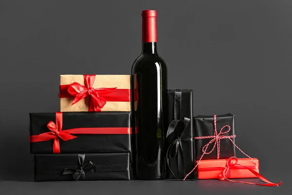 Bottle of wine and Christmas gift boxes on black background