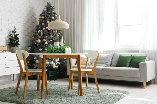 Stylish interior of light living room with mistletoe wreath and burning candles on table