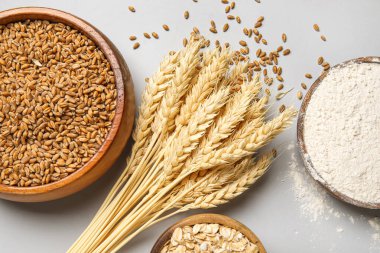 Tahta kaseler tahıl ve un ile gri arka planda buğday kulakları