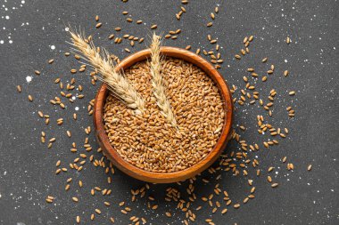 Tahta kasede tahıllar ve grunge siyah arka planda buğday kulakları.