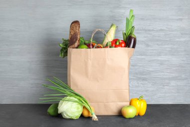 Siyah masanın üzerinde farklı ürünler olan kağıt torba.