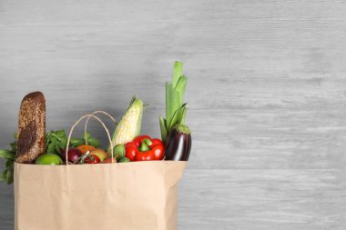 Gri zemin üzerinde farklı ürünler bulunan kağıt torba.