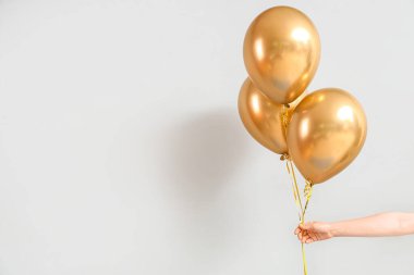 Doğumgünü kutlaması için arka planda altın balonlu bir kadın eli
