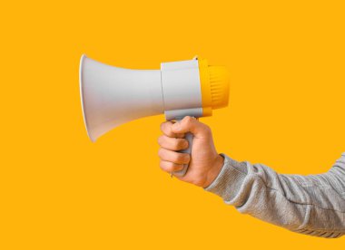 Sarı arka planda megafonu olan genç bir adam.