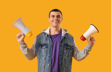 Sarı arka planda megafonları olan genç bir adam.