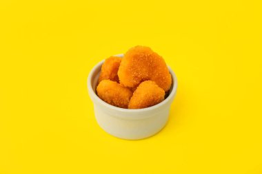 Sarı arka planda lezzetli nuggetlarla dolu bir kase