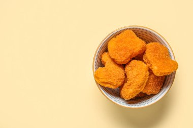 Sarı arka planda lezzetli nuggetlarla dolu bir kase