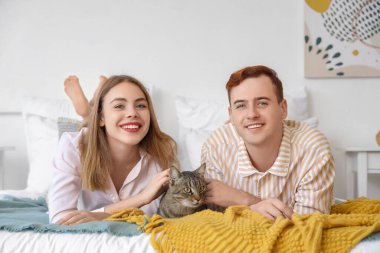 Yatak odasında tatlı kedileri olan genç bir çift.