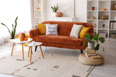 Oturma odasının içinde kırmızı kanepe ve masalar.