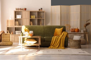 İçinde yeşil kanepe ve balkabağı olan oturma odasının içi.