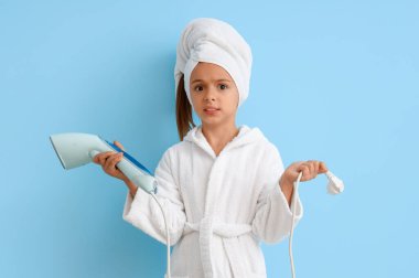 Mavi arka planda buharlı bornozlu küçük kız şok oldu.