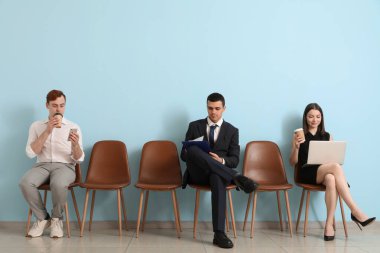 Başvuranlar iş görüşmesi için mavi duvarın yanında bekliyorlar