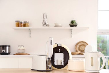 Hafif mutfakta modern aletler bulunan ahşap masa.