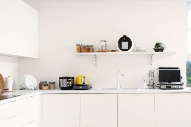 Beyaz tezgahlarda modern aletlerle aydınlık mutfak.