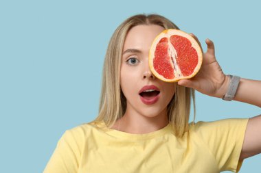 Mavi arka planda greyfurtlu genç kadın, yakın plan.