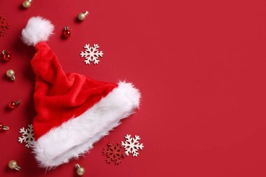 Kırmızı arka planda Noel Baba şapkası ve Noel süslemeleri