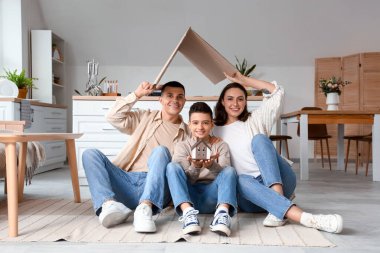 Ev modeli olan küçük bir çocuk ve anne babası mutfakta.