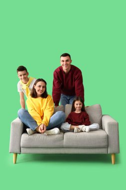 Yeşil arka planda aileleri ve kanepesi olan küçük çocuklar.