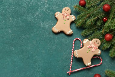 Noel tatlı zencefilli kurabiyeler, baston şekerler ve yeşil arka planda topları olan köknar dalları.