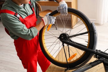 Erkek tamirci atölyede bisiklet tekerleğini tamir ediyor