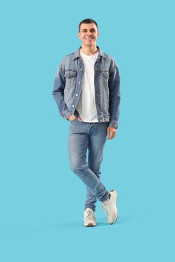 Mavi arka planda kot elbiseli şık genç adam.