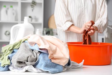 Kirli çamaşır yığını ve çamaşırları leğende yıkayan kadın.