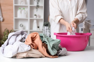 Kirli çamaşır yığını ve çamaşırları leğende yıkayan kadın.