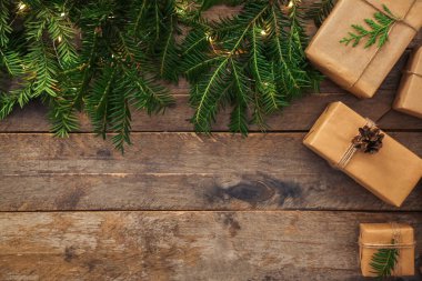 Çam kozalaklı hediye kutuları, köknar dalları ve ahşap arka planda parlayan Noel ışıkları