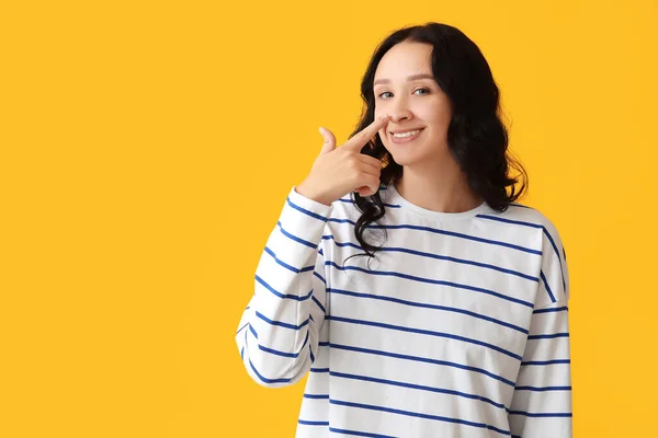 Retrato Uma Jovem Bonita Tocando Seu Nariz Fundo Amarelo — Fotografia de Stock