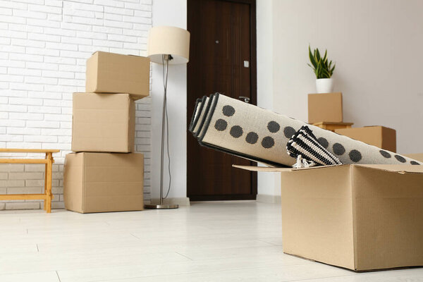 Картонная коробка с катанными коврами в комнате в день переезда, крупный план