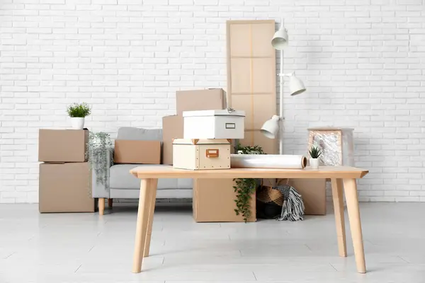 Table with boxes and stretch wrap in living room on moving day