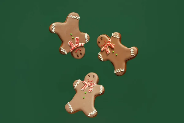 Three gingerbread cookies on green background.