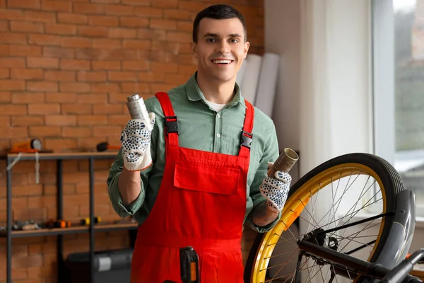 Male mechanic with bicycle parts in workshop
