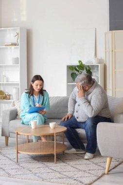 Hemşire evde olgun bir adamla panoya yazı yazıyor.