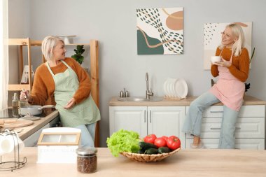 Mutfakta yemek pişiren olgun bayan arkadaşlar.