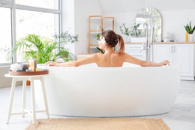 Çiçekli güzel bir kadın evde banyo yapıyor, arkadan bakıyor.