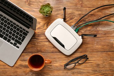 Laptoplu modern kablosuz yönlendirici ve ahşap arka planda bir fincan çay.
