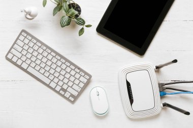 Beyaz ahşap arka planda klavye ve tablet bilgisayarlı modern wi-fi yönlendirici