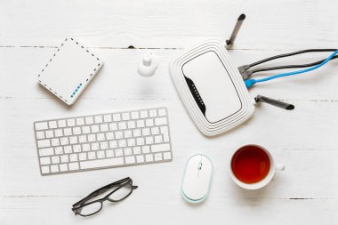 Klavyeli modern wi-fi yönlendirici ve beyaz ahşap arka planda bir fincan çay.