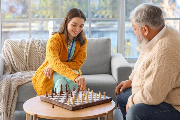 Mature man with nurse playing chess at home