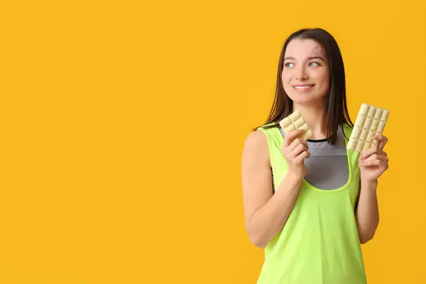 黄色の背景に白いチョコレートバーを持つ若い女性 — ストック写真