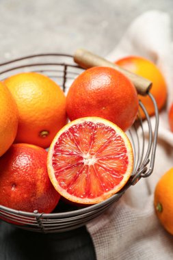Gri arka planda lezzetli kan portakalları olan metal sepet.
