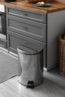 Modern mutfakta yerde metal çöp kutusu var.