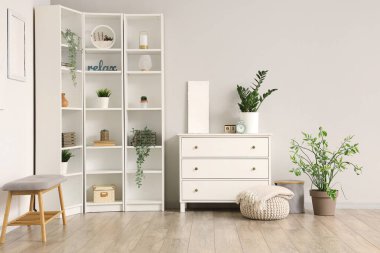 Aydınlık oturma odasının iç tarafında yumuşak battaniyeli çekmeceler ve puf.