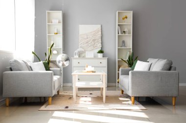 Modern oturma odasının içinde gri kanepeler, asılı disko topu ve kahve masası.