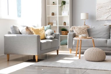 Gri kanepeleri, disko topu ve kahve masası olan modern oturma odasının içinde.