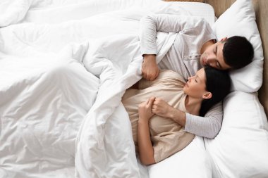 Yatak odasında uyuyan genç bir çift.