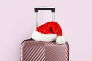 Renkli arka planda Noel Baba şapkası olan şık bavul, yakın plan.