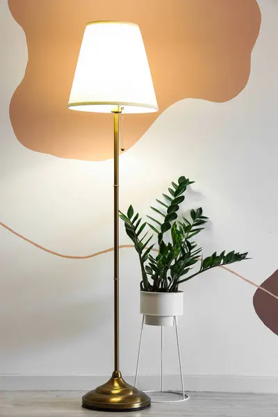 Glowing stand lamp with houseplant in room